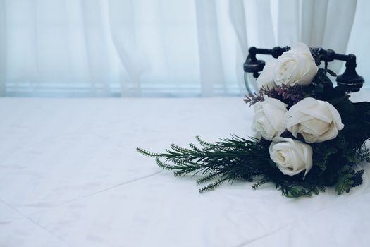 white bridal wedding rose flower bouquet on bed beside see through sheer window curtain