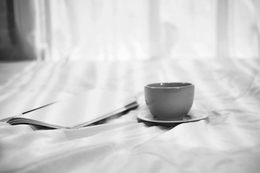coffee cup notebook on white bed in bedroom