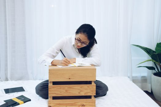 asian woman writing note on working bed in bedroom.