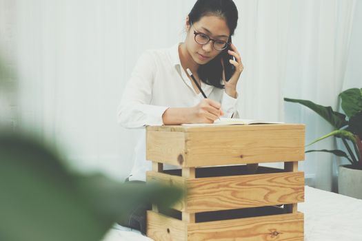 freelancer woman businesswoman talking on mobile phone writing note on bed at home