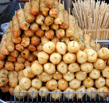 An outdoor vendor sells fried fish balls and fish sausages

