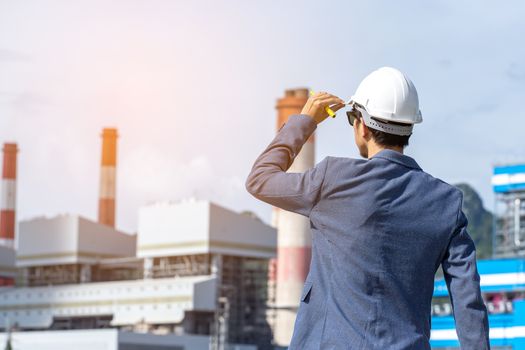 Engineer with a coal power plant in the background, Thailand