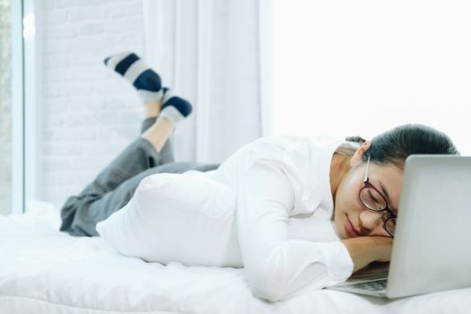 woman sleeping lying resting on bed laying head on computer laptop at home