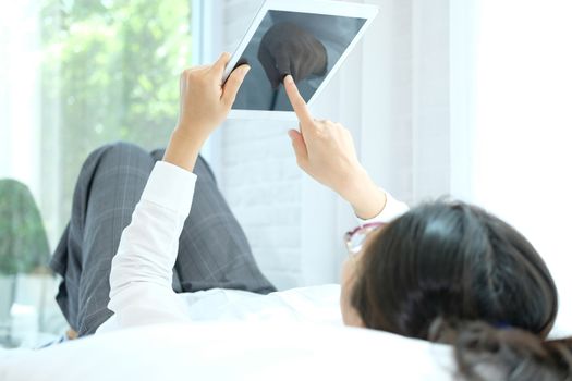 woman using digital tablet lying on bed at home