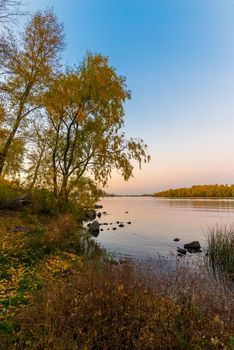 Trees and  warm colors of the Dnieper river at dusk in autumn, in Kiev, Ukraine