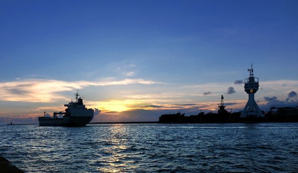 A large cargo ship leaves Kaohsiung Port at sunset
