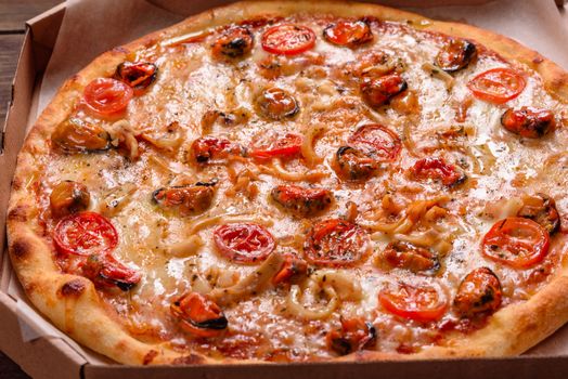 Seafood Italian pizza with shrimp, squid, mussels, fresh herbs and mozzarella on a
dark background. Tasty sliced pizza with seafood and tomato on a concrete background