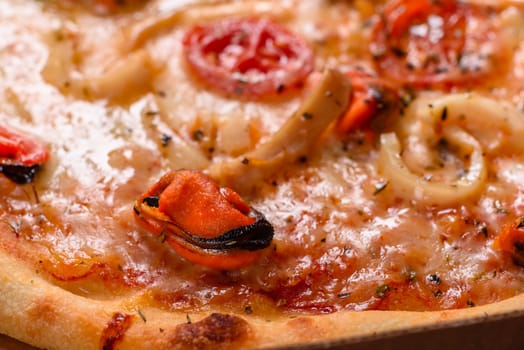 Seafood Italian pizza with shrimp, squid, mussels, fresh herbs and mozzarella on a
dark background. Tasty sliced pizza with seafood and tomato on a concrete background