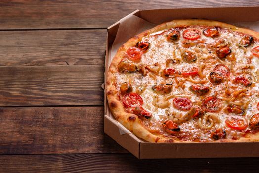 Seafood Italian pizza with shrimp, squid, mussels, fresh herbs and mozzarella on a
dark background. Tasty sliced pizza with seafood and tomato on a concrete background