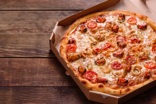 Seafood Italian pizza with shrimp, squid, mussels, fresh herbs and mozzarella on a
dark background. Tasty sliced pizza with seafood and tomato on a concrete background