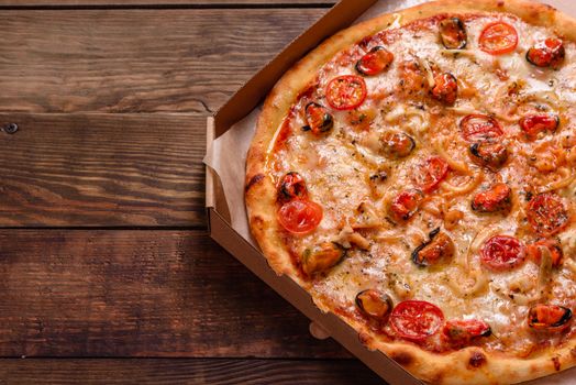 Seafood Italian pizza with shrimp, squid, mussels, fresh herbs and mozzarella on a
dark background. Tasty sliced pizza with seafood and tomato on a concrete background