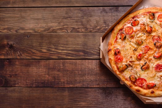 Seafood Italian pizza with shrimp, squid, mussels, fresh herbs and mozzarella on a
dark background. Tasty sliced pizza with seafood and tomato on a concrete background