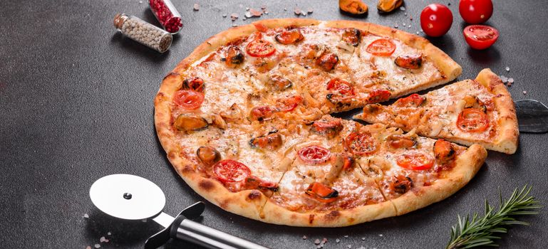 Seafood Italian pizza with shrimp, squid, mussels, fresh herbs and mozzarella on a
dark background. Tasty sliced pizza with seafood and tomato on a concrete background