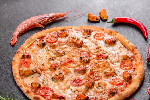 Seafood Italian pizza with shrimp, squid, mussels, fresh herbs and mozzarella on a
dark background. Tasty sliced pizza with seafood and tomato on a concrete background