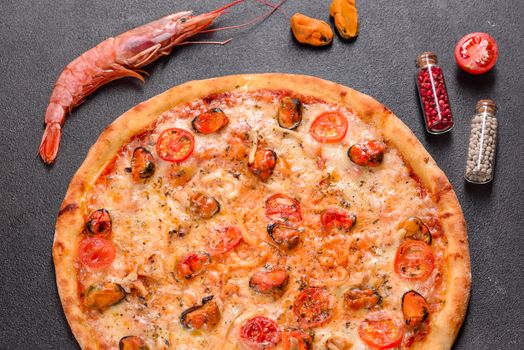 Seafood Italian pizza with shrimp, squid, mussels, fresh herbs and mozzarella on a
dark background. Tasty sliced pizza with seafood and tomato on a concrete background