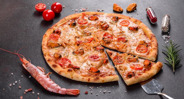 Seafood Italian pizza with shrimp, squid, mussels, fresh herbs and mozzarella on a
dark background. Tasty sliced pizza with seafood and tomato on a concrete background