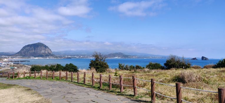 A paved foot path in songaksan mountain with sanbang-san mountain in background in Jeju Island, South Korea