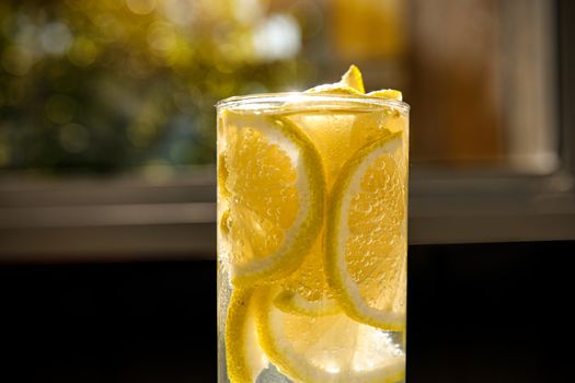 Glass of lemon water on the sunny garden background. Close-up view