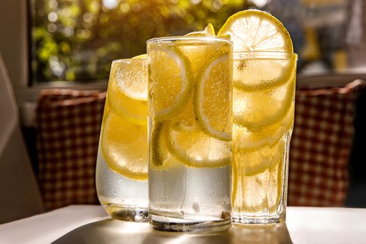 Glasses of lemonade with lemon on the sunny room background