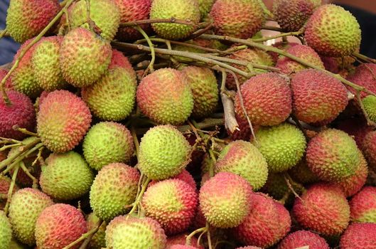 Bundles of fresh lychee fruit are sold at an outdoor market