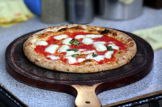 Pizza margherita with tomatoes, cheese and fresh basil placed on a cutting board