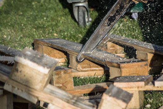 A wooden pallet being cut up with a chainsaw.