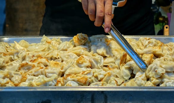 An outdoor vendor sells fried dumplings or pot-stickers
