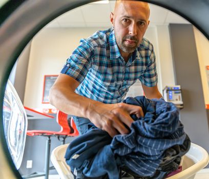 a man putting his underwear in the laundry room.