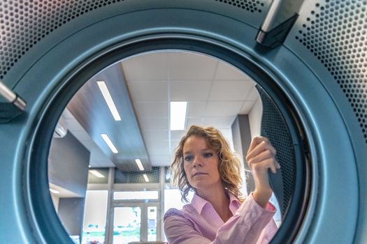 view of a woman into a washing machine in a laundry room.