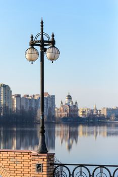 A street lamp close to the river with buildings and church in the background