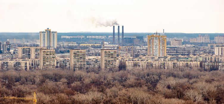 Panoramic view of the Kiev's left bank from the Park of Eternal Glory. Trees, buildings and factories with high smoking chimneys appear in the distance