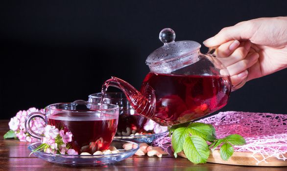 A woman pours tea into a Cup. Red tea, hibiscus, karkade, Rooibos. Ceremony, afternoon tea, Breakfast. Tea time, carcade. Oriental, cozy, tradition, japanese, leafy, hygge, autumn, 5 o'clock, mug