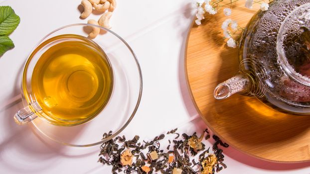 A Cup of green tea and a teapot. Flower tea with fruit slices. Tea ceremony, traditional drink. Afternoon tea, homelike. Flat lay. Oriental, cozy, preparation, heat, tradition, japanese, leafy, herbal