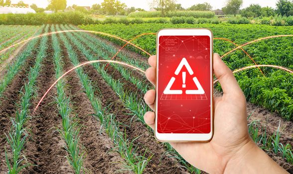 The phone warns of the danger on the farm field. Monitoring and analysis of presence of chemicals, heavy metals, pollution, radiation or microplastics in the crop. Health hazard, harmful substances.