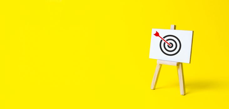 Sign stand with an arrow in the target on a yellow background. Hit exactly on center. Tactics of advertising targeting. advertise campaigns. Goal Achievement and Purposefulness