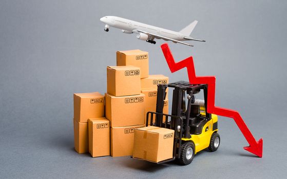 Cargo airplane, forklift truck with cardboard boxes and a red arrow down. Drop in industrial production and business. Decrease freight transportation and volumes of delivery of products and goods.