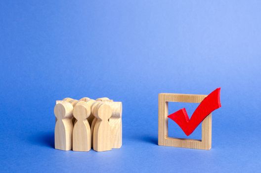 Crowd of people looking at a red wooden checkmark for voting on elections on a blue background. Presidency or parliamentary elections, a referendum. Survey of the population, statistics completed task