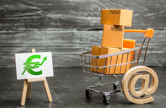 A shopping cart with boxes symbolizing internet trading and a stand with a green Euro up arrow. shopping online. sales of goods and services. Internet network trade, advertising services. E-commerce.