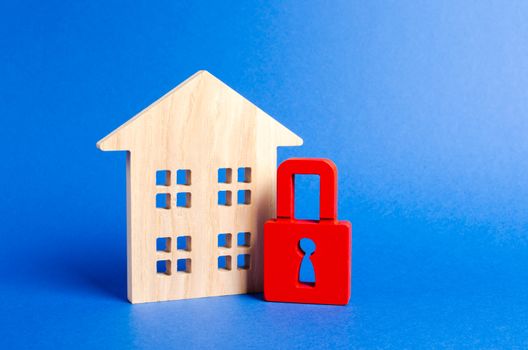 Wooden house and a red padlock. Security and safety. Confiscation for debts. alarm system. seizure of property. Protection of property rights. Unavailable and expensive real estate. house Insurance