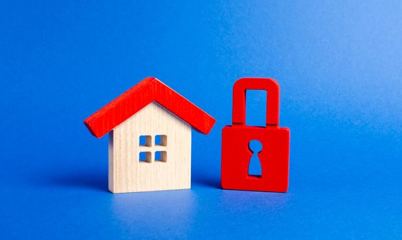 A wooden house and a red padlock. Unavailable and expensive real estate. house Insurance. Security and safety. Confiscation for debts. alarm system. seizure of property. Protection of property rights.