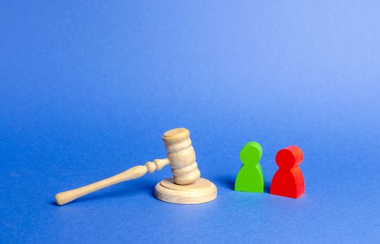 Two figures of people opponents stand near the judge's gavel. The judicial system. Conflict resolution in court, claimant and respondent. Court case, settling disputes. Legal advice, lawyer services.