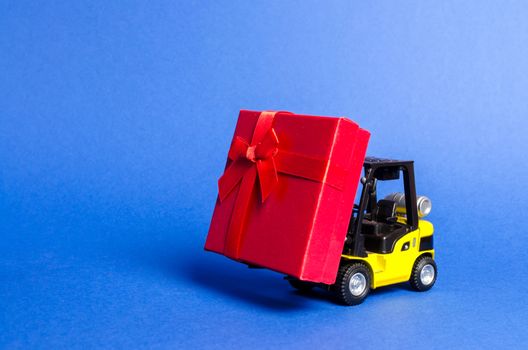 Yellow forklift truck carries a red gift box with a bow. Purchase and delivery of a present. retail, discounts and contests. contest promotions. Increase sales and attract new customers.