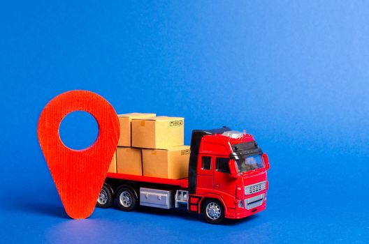 A red truck loaded with boxes and a red pointer location. Services transportation of goods, products, logistics and infrastructure. Transportation company. Location of carriers. Package tracking