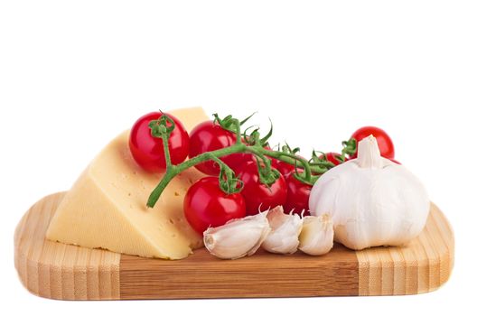 Tomatoes, garlic and cheese on a wooden cutting board over the white background