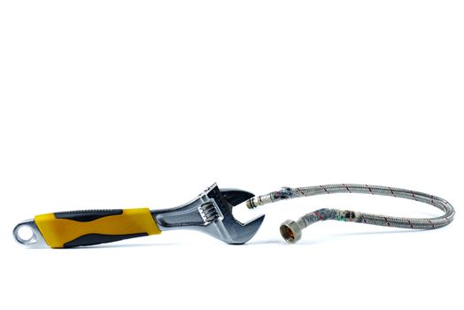 Old damaged armored cold water hose and universal pipe wrench isolated on white background