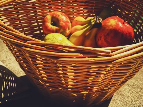 Organic apples, pears and bananas on rustic in a wicker basket, fruits farming and agriculture