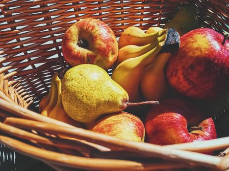 Organic apples, pears and bananas on rustic in a wicker basket, fruits farming and agriculture