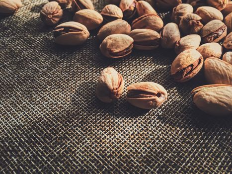 Pistachio nuts on rustic linen background, food and nutrition