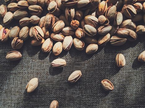 Pistachio nuts on rustic linen background, food and nutrition