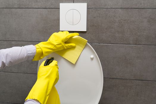 Men in yellow gloves cleaning toilet bowl. home cleaning concept